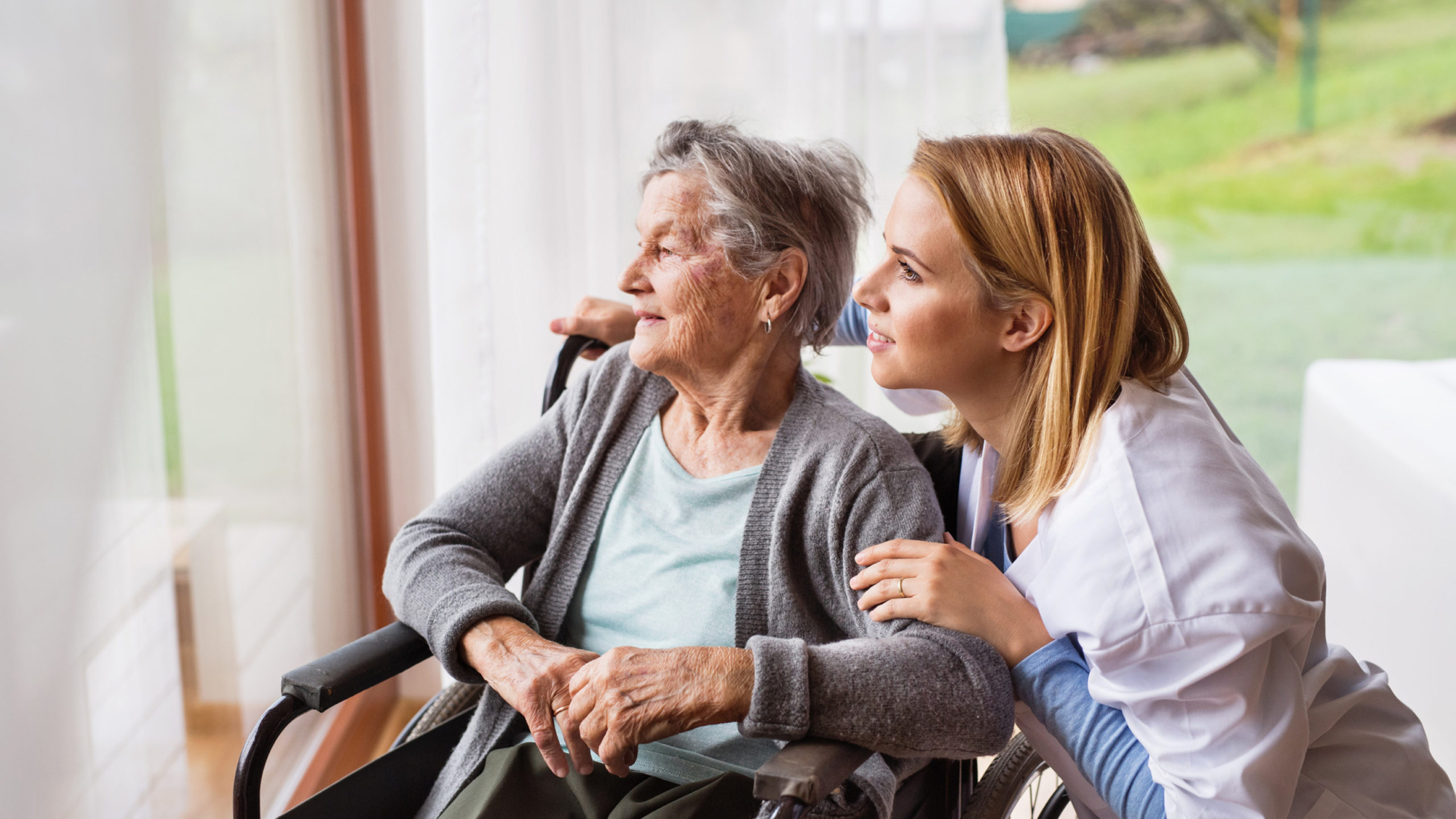 Health visitor and a senior woman during home visit. A nurse talking to an elderly woman in an wheelchair.