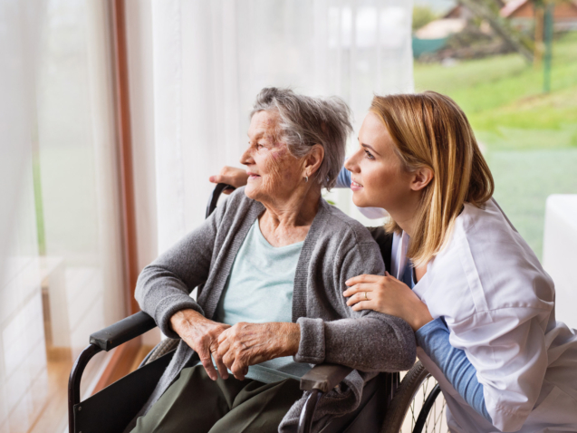 Health visitor and a senior woman during home visit. A nurse talking to an elderly woman in an wheelchair.